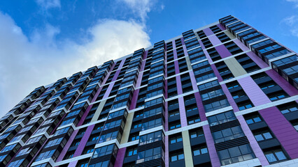 The facade of the building in purple,geometric patterns from windows and balconies, the colored wall of a modern multi-storey residential building, the abstract texture of the facade of the house