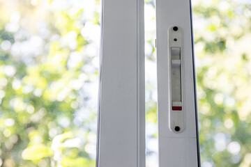 Close-up of a double-glazed balcony frame with a latch and fastening for safe ventilation. Single-sided window handle. House door and window repair concept
