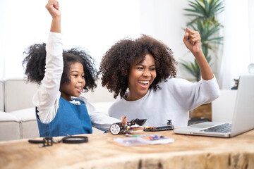 African loving mother and daughter enjoy for a fun robotics project at home, exploring hands-on STEM activities that inspire creativity, and early engineering skills, fostering problem-solving skills