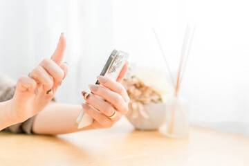 スマホ・スマートフォンの画面をタッチするネイルをした女性
