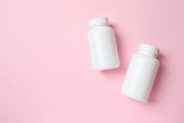 White bottles on pink background, top view