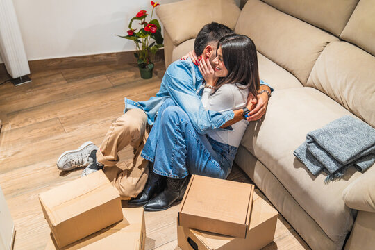 Happy couple embracing on living room floor after moving into new home