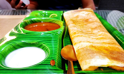 South indian food crispy Masala Dosa with sambar and chutney on banana leaf style plate