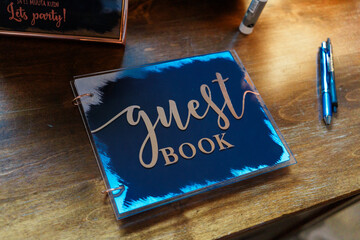 Black guest book on a wooden table in a restaurant with a pen