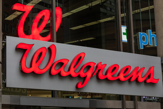 Boston, MA, USA - Dec 24, 2020 - A Walgreens pharmacy storefront with a bright red illuminated sign reflecting on the glass windows in downtown Boston