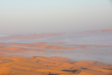 Sand dunes of Liwa desert in fog during sunrise hours.