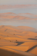 Sand dunes of Liwa desert in fog during sunrise hours.