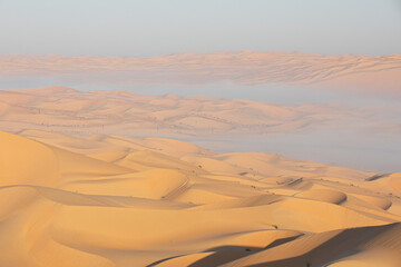 Sand dunes of Liwa desert in fog during sunrise hours.