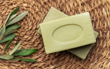 Olive soap bars resting on a woven mat with olive branch