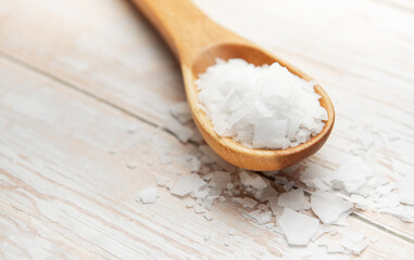 Wooden spoon holding magnesium chloride flakes on white table