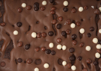Chocolate brownie cake texture background sprinkled with white and dark balls, brounie banner
