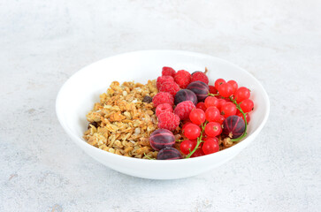 Granola with fresh berries in a white bowl isolated