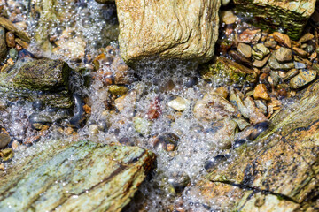 Foamy Water Flowing Over Colorful Pebbles