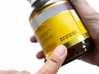 Expire drugs Check, finger woman pointing mfg and exp date infomation on bottle supplement food product, blur medicine label.