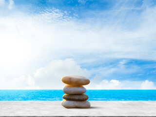 Stone stack on mockup table cement with blue sea and blue sky background, zen pyramid meditation pebble relaxation nature balance, concept calm vacation therapy happiness.