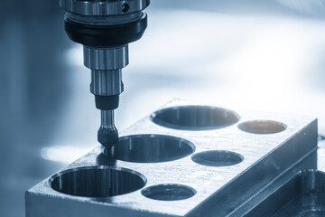 The CNC milling machine chamfer cutting automotive part in the light blue scene.