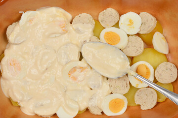 A top-down shot of peeled, boiled potato slices, sausage slices, and hard-boiled egg slices...