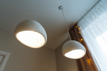 Two elegant pendant lights are delicately hanging from the ceiling in a beautifully designed room,...