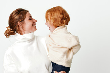 Mother and daughter embracing in white sweaters on a serene background, concept of love and family bonding