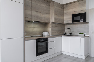Modern kitchen with cabinets and induction on counter, built-in oven, microwave. kitchen with white...