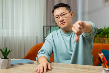 Dislike. Upset unhappy middle-aged Chinese man showing thumbs down sign gesture, expressing...