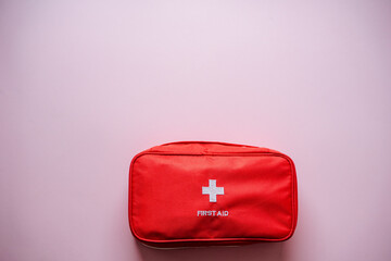 A vibrant red first aid kit against a soft pink background is perfect for home, travel, and outdoor...