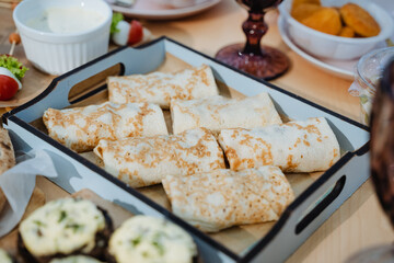 A tray filled with a variety of delicious food items is currently resting on a rustic wooden table, creating an inviting atmosphere for a meal. It showcases diverse culinary delights