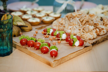 On a crafted wooden cutting board, colorful tomatoes and creamy mozzarella arranged on skewers...