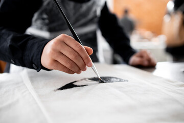 Asian adult engaged in painting artistic project with precision and skill