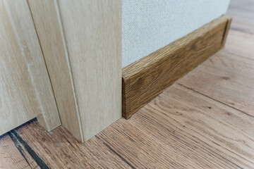 This image shows a detailed closeup of a beautifully crafted wooden skirting board, aligning with a polished floor by a spacious doorway, enhancing the rooms charm and visual appeal