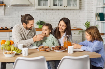 Parents and children laughing while celebrating a holiday at home. Sitting together at the dinner table in the kitchen, the family enjoys food, joy, and togetherness during a festive and cheerful day.
