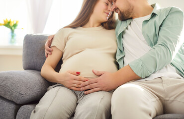 Loving couple sitting belly hug, future parents expecting first baby close at home, caring husband...