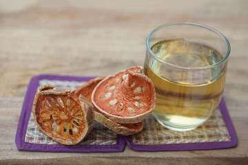 Bael fruit herbal drink in clear glass. Concept healthy drink with medicinal property, made from dried sliced bael, boiled in water, can drink as hot tea or iced beverage.     