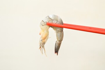 raw seafood shrimp picked up with chopsticks, healthy snack. for background, copy space, design