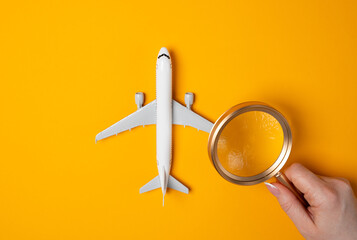 A woman examines a passenger plane under a magnifying glass. Airline monitoring. Performance...