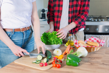 Young couple preparing a meal chopping vegetables in kitchen at home, healthy lifestyle.