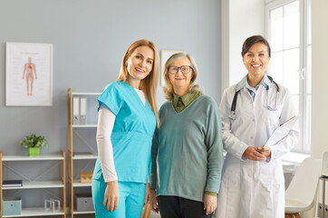 Fototapeta premium Caring kind smiling nurse, doctor, geriatric medicine caretaker with senior woman in clinic to help, support aged old during medical visit in retirement home, hospital, female caregiving service, meet