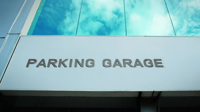 Parking garage sign on a modern building with a reflection of the sky on glass windows, symbolizing convenience, transportation, and urban infrastructure