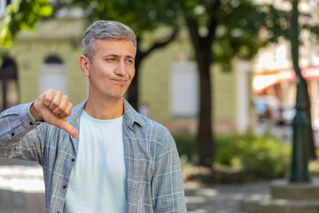 Dislike. Upset middle-aged man male showing thumb down sign gesture expressing discontent...
