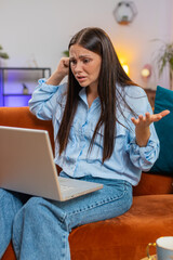 Angry stressed young Caucasian woman talking laptop using computer webcam video call on couch...