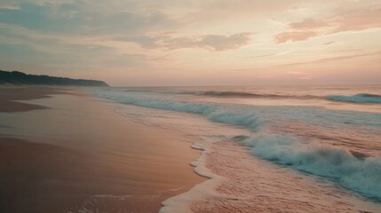 Obraz premium A slow-motion capture of ocean waves rolling onto a sandy shore, with soft pastel hues in the sky, representing the calming rhythm of nature's tides 