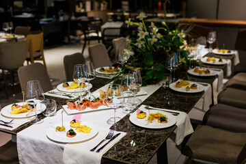 Luxurious dining table setup featuring gourmet appetizers, elegant glassware, floral centerpiece
