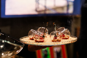 Elegant gourmet appetizers served in tilted glassware on a stylish crystal platter