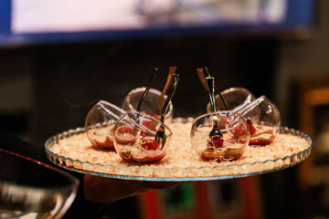 Elegant gourmet appetizers served in tilted glassware on a stylish crystal platter