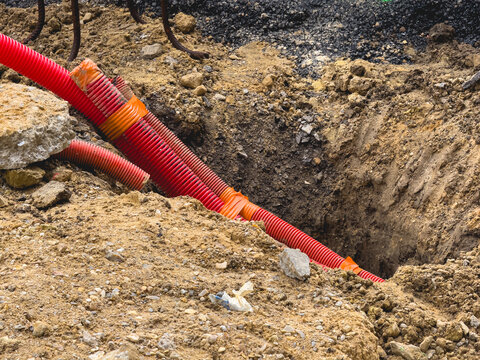 Une gaine rouge &eacute;lectrique dans le sol pour des travaux de voirie.