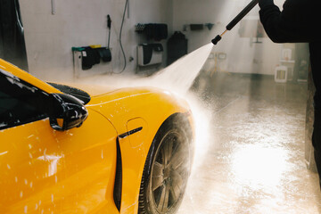 Detailing process of washing car from water gun at the car wash. Washing sports car using...