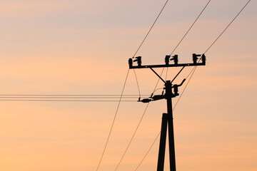 Electrical pole with electrical cables on a beautiful gold sky background 
