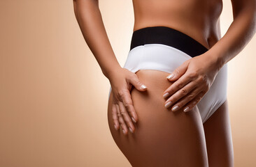 Woman with cellulite on light brown background, closeup