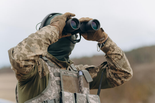 Soldier Observing Terrain with Binoculars During Surveillance Operation