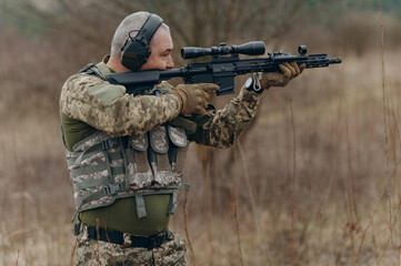 Fototapeta premium A soldier aiming with a rifle in tactical gear on the shooting range